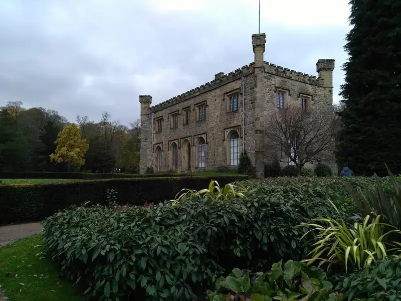 The castellated stone front of Towneley Hall in Burnley, behind clipped hedges and shrubs