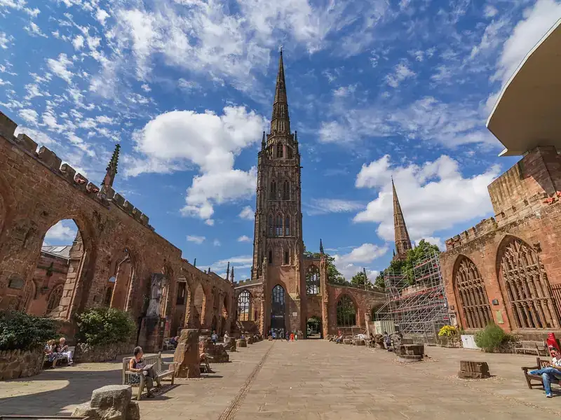 The spire of Coventry's old cathedral rising above the open ruins under a blue sky