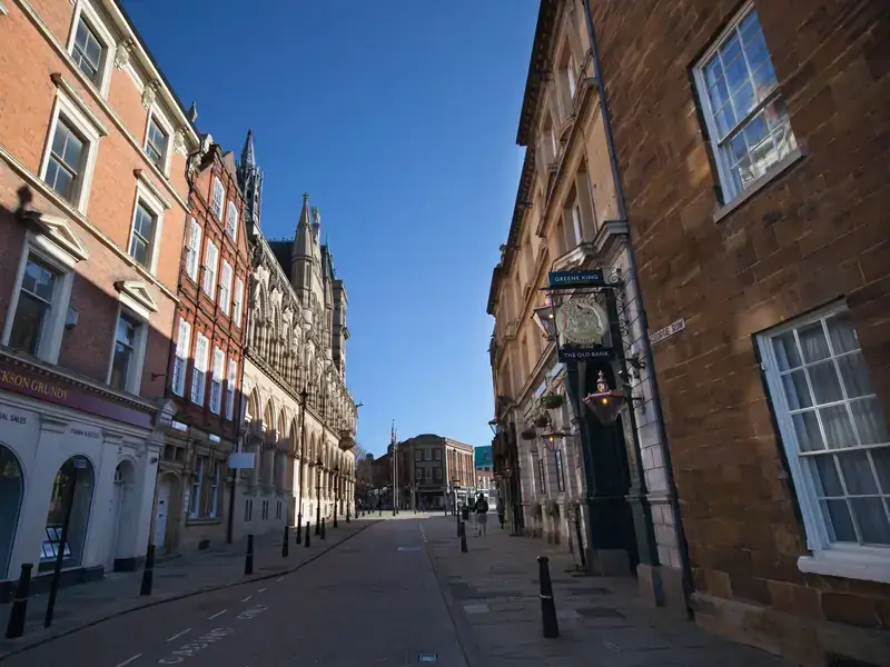 A sunny street of red-brick and stone buildings leading past the Guildhall in Northampton town centre