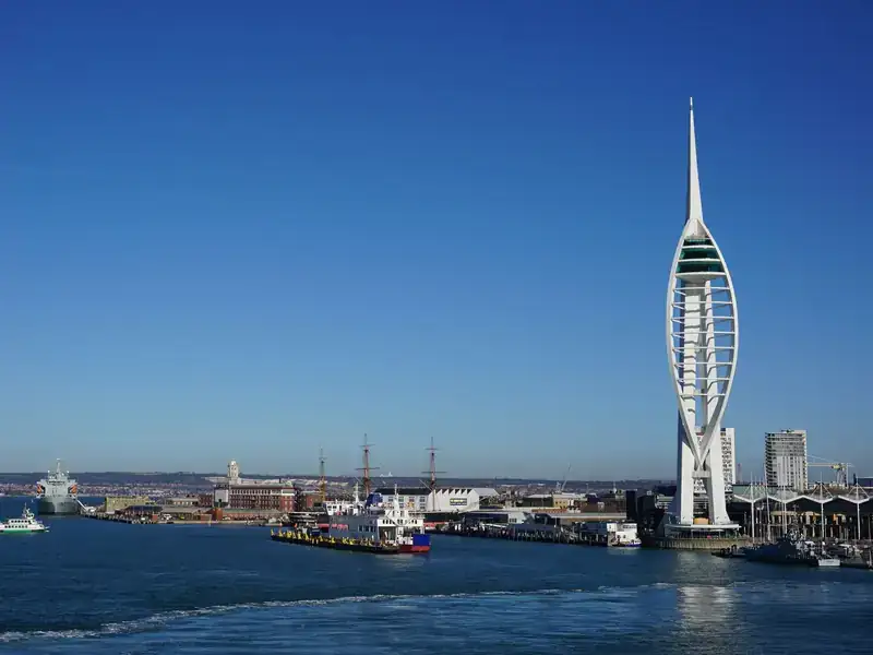 The Spinnaker Tower beside Portsmouth Harbour, with ships and the Historic Dockyard under a clear blue sky