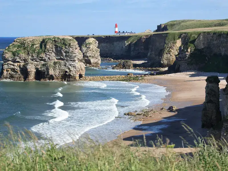 Marsden Bay in South Shields, with sea stacks, a sandy beach and Souter Lighthouse on the cliffs