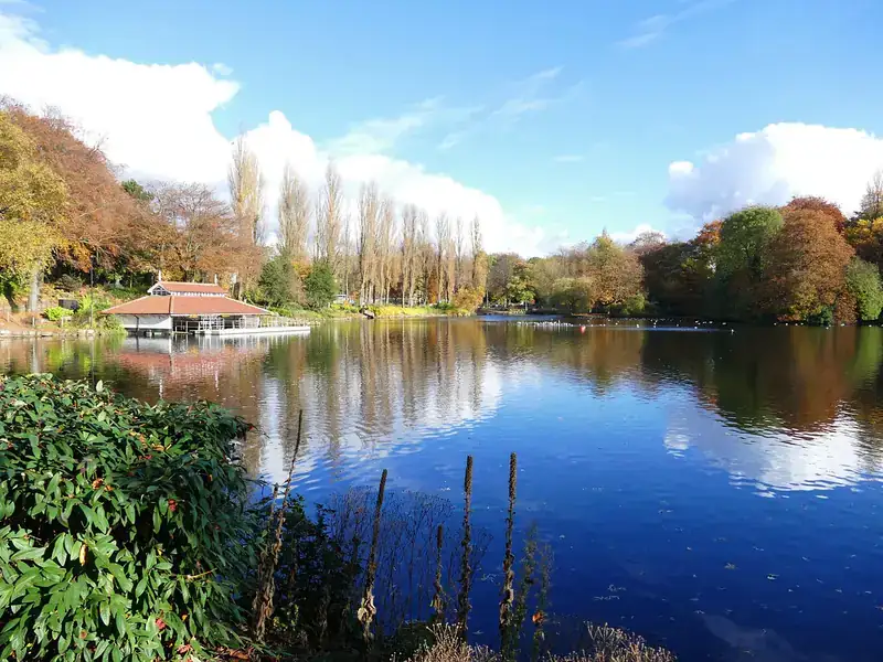 The boathouse and autumn trees reflected in the lake at Walsall Arboretum