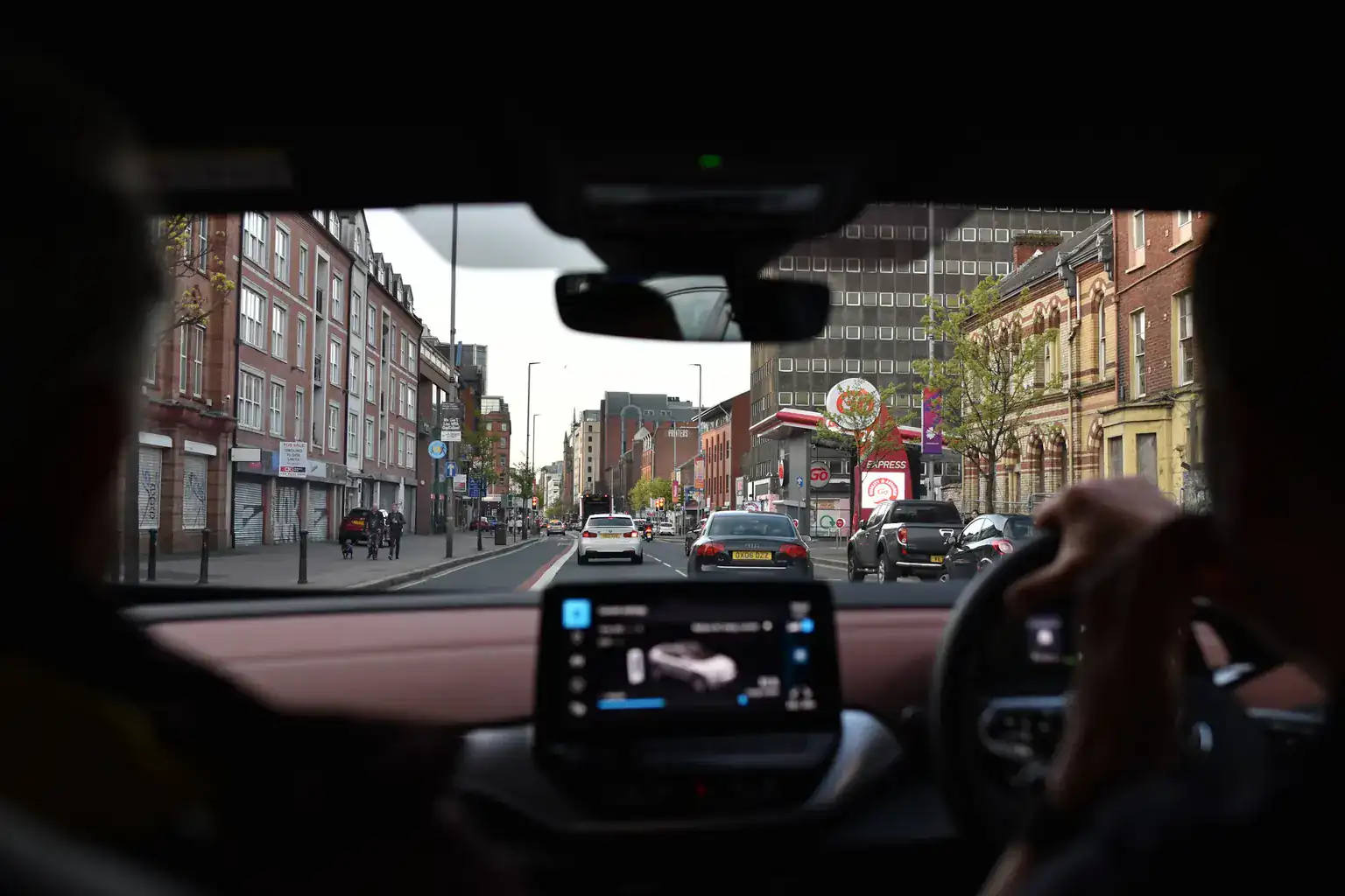 View from the back seat of a right-hand-drive car driving along a busy UK high street