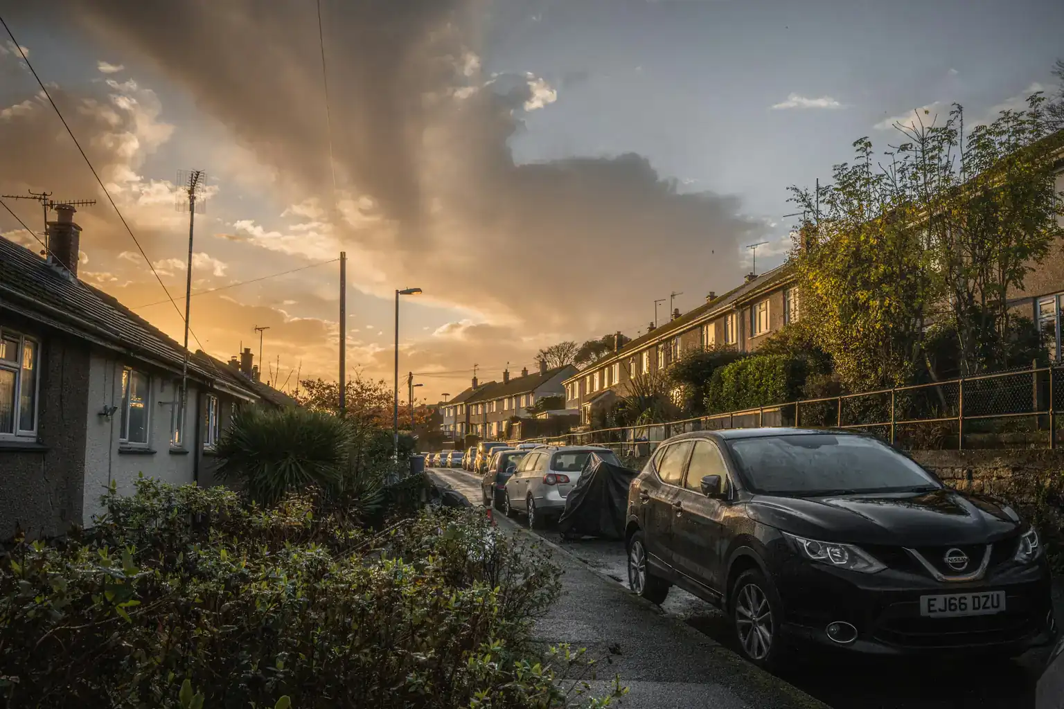 A dark family SUV parked on a British residential street at sunset