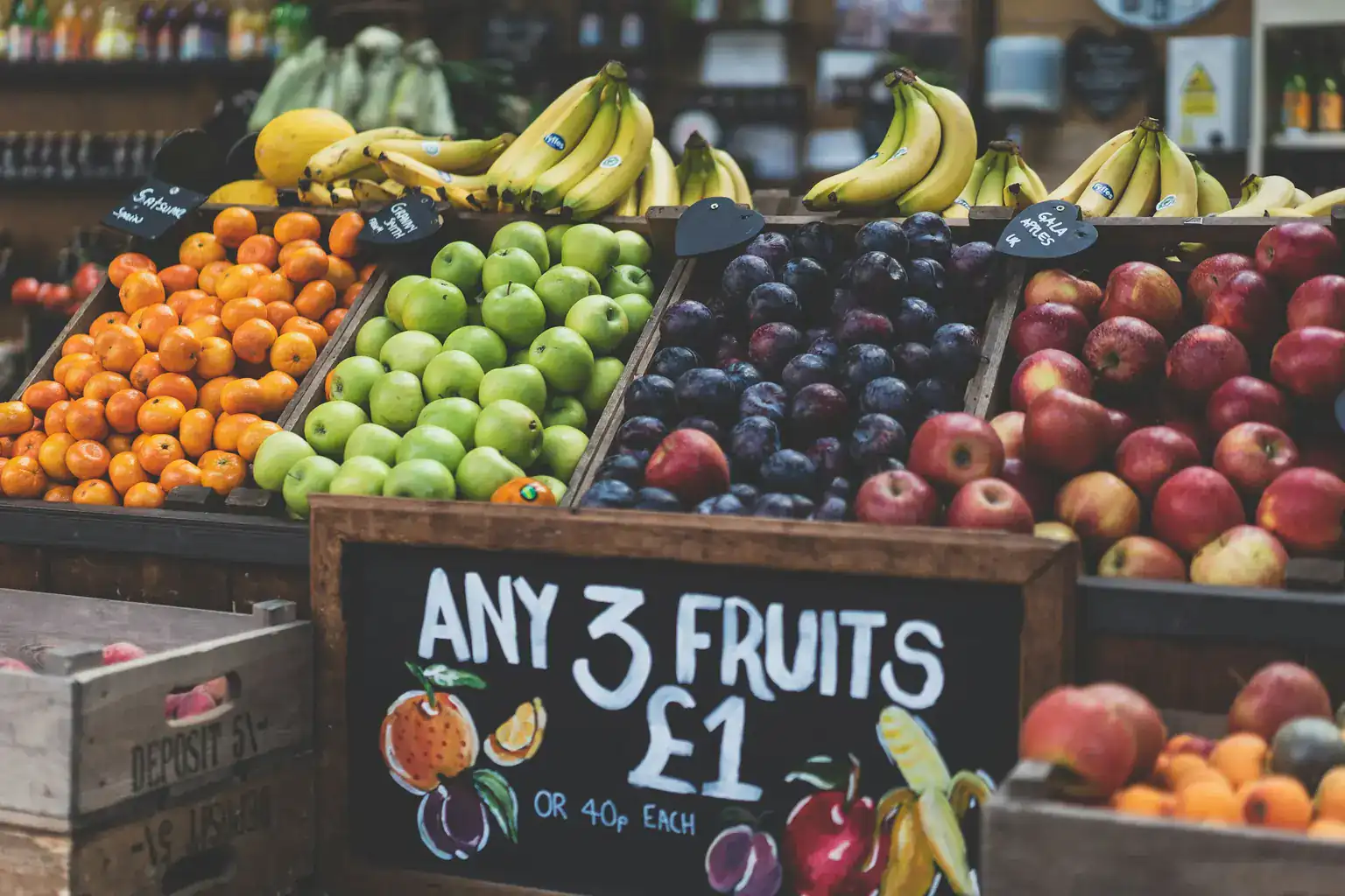 A London market fruit stall with a chalkboard offering any three fruits for one pound