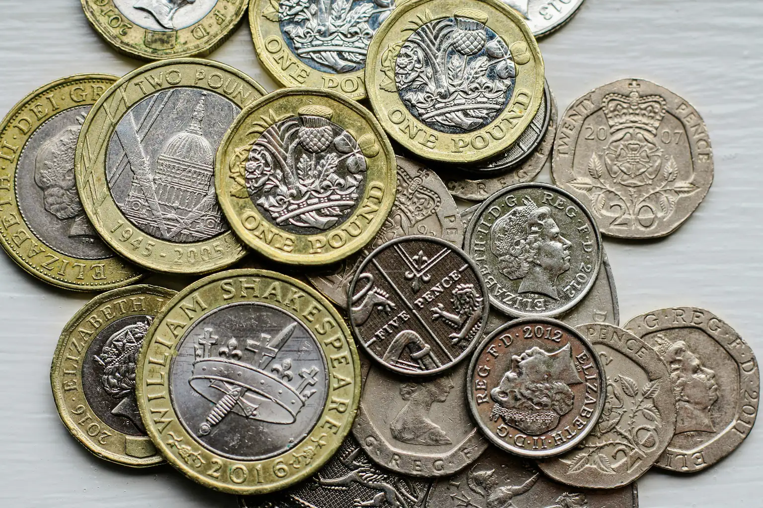 A pile of British coins including one and two pound coins and twenty pence pieces